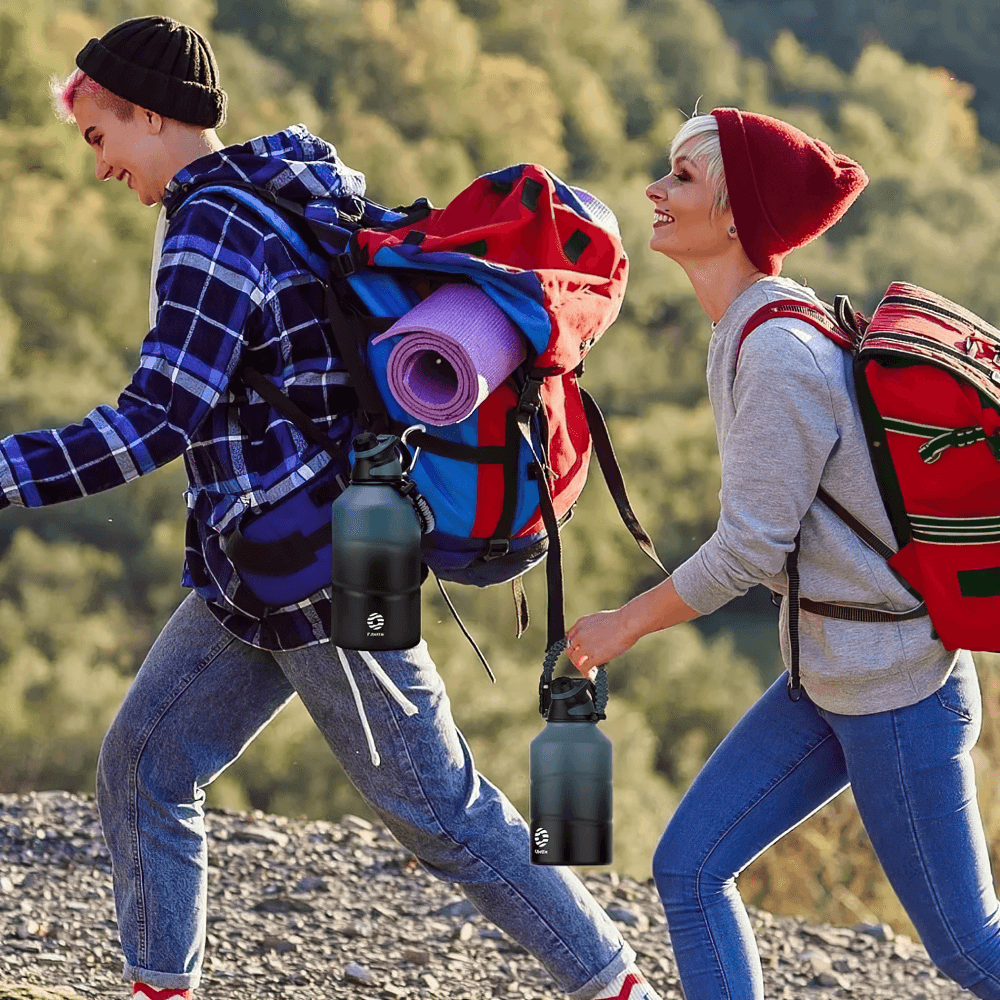 Two hikers with backpacks and stainless steel thermos bottles enjoying a trail hike, showcasing the thermos's portability and durability.