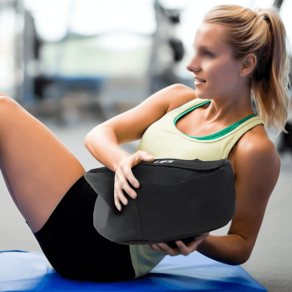 Woman using 100 LB Strongman Sandbag for core workout, highlighting fitness and endurance at home gym.