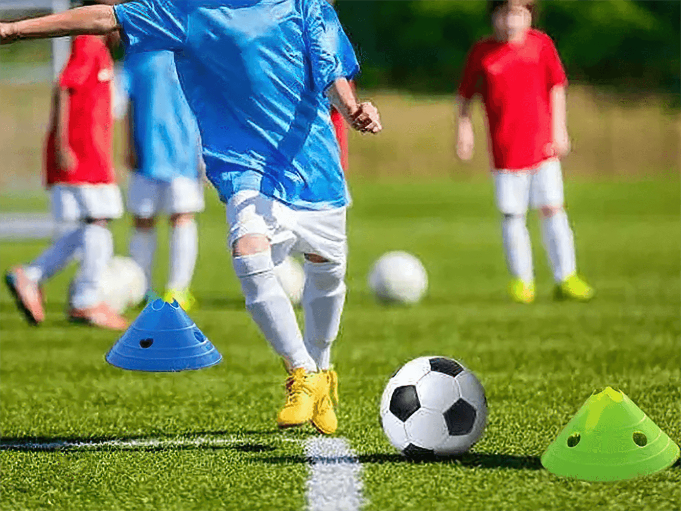 Young player in blue jersey practicing soccer with colorful 15cm agility cones on the field.