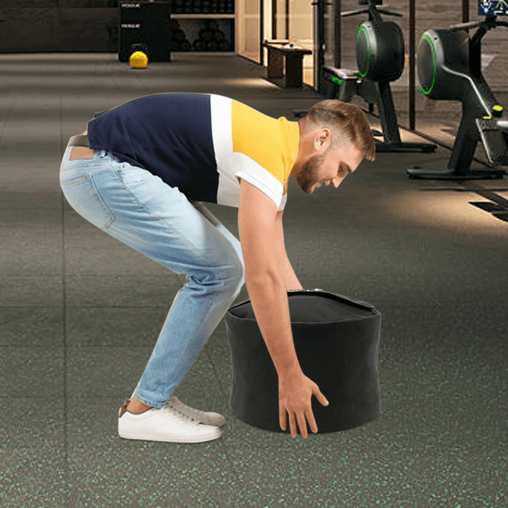 Man lifting a heavy-duty sandbag in gym, ideal for CrossFit and power training, promoting muscle stability and endurance.