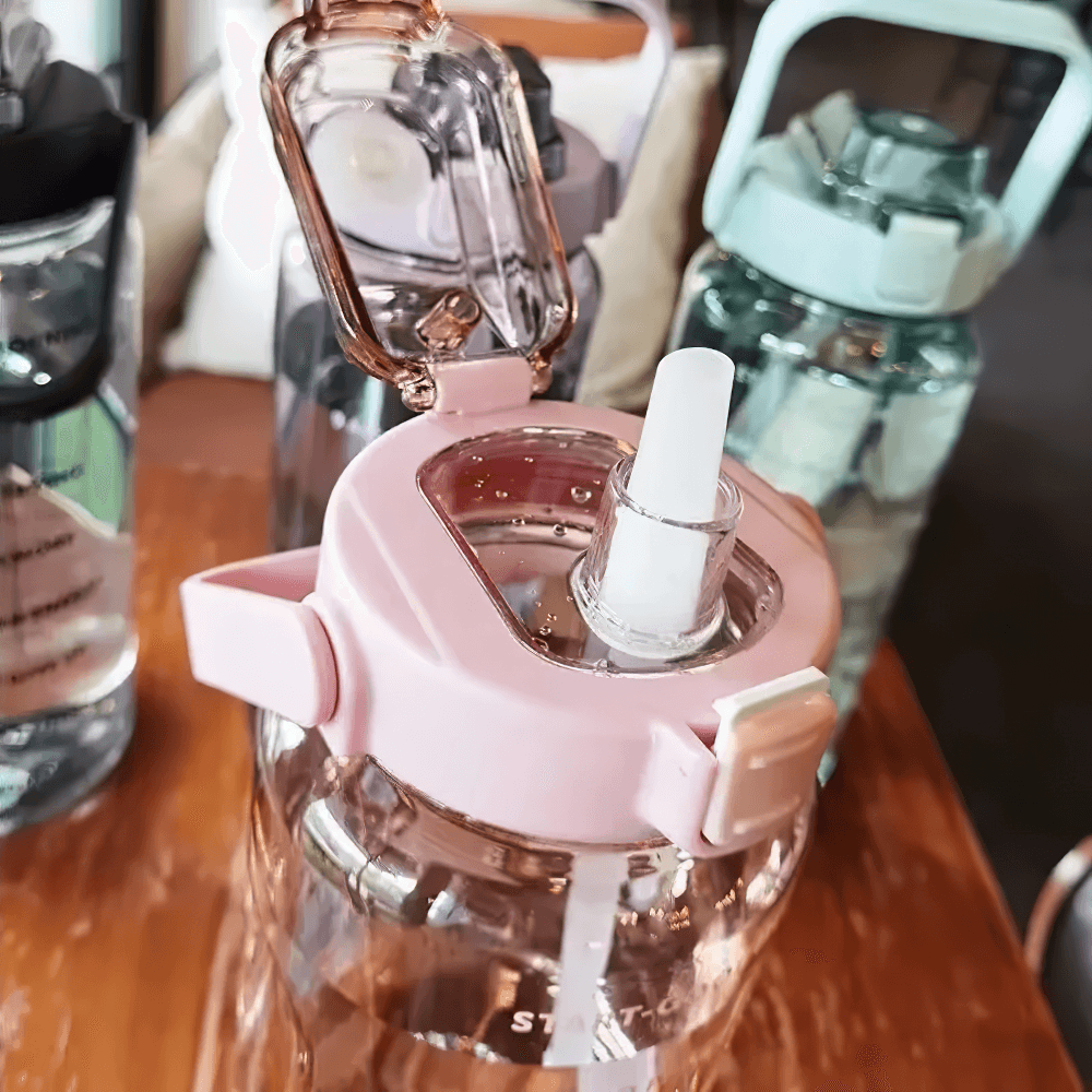 Large pink sports water bottle with straw and handle, perfect for gym or outdoor activities. Eco-friendly plastic for hydration goals.