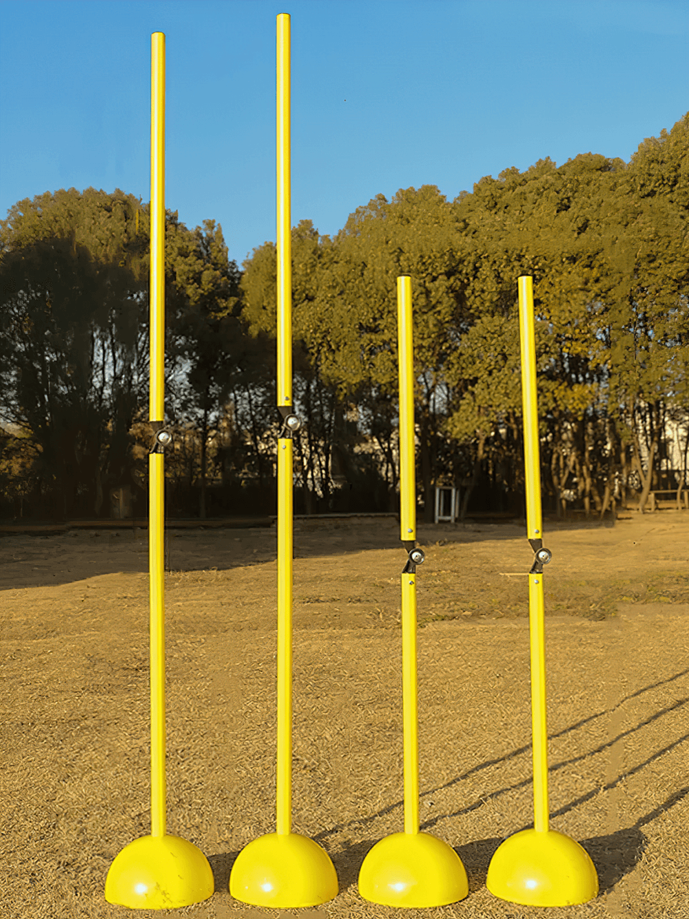 Adjustable yellow agility poles for football training in an outdoor setting, perfect for soccer drills and dynamic hurdle exercises.
