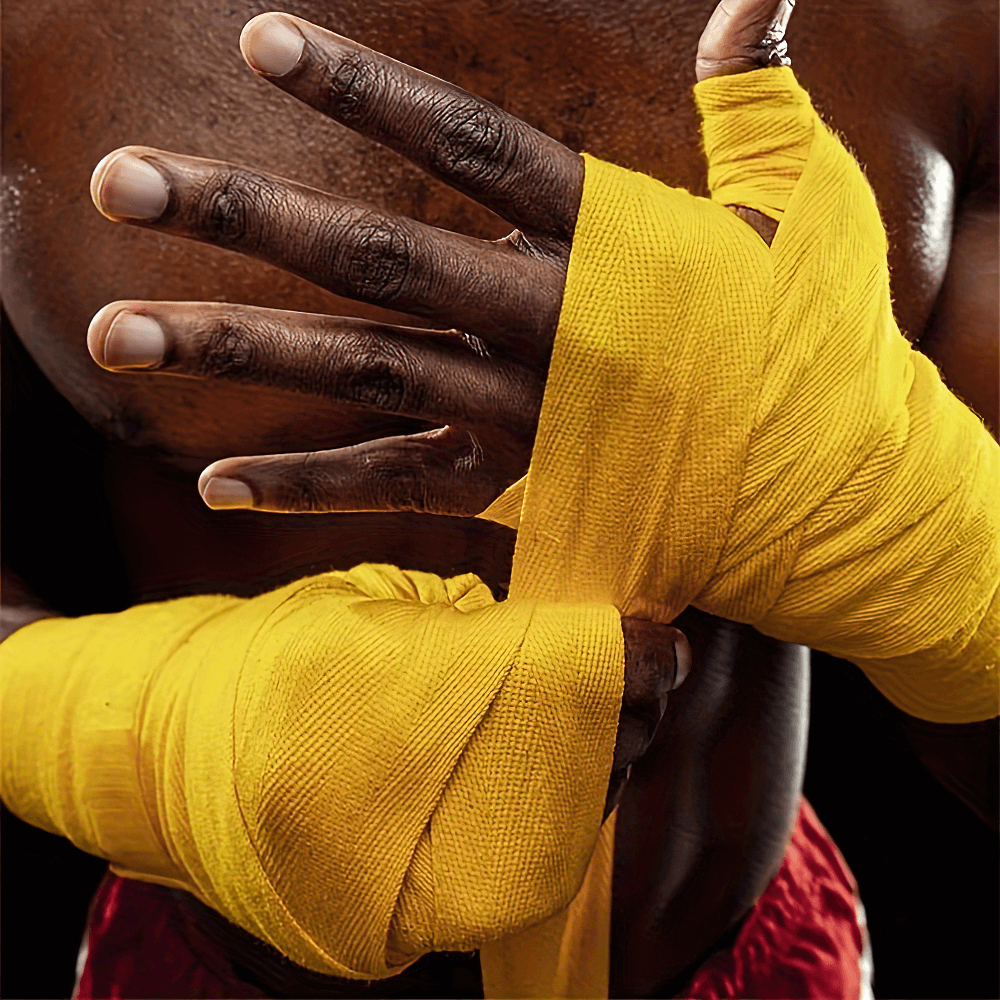 Person wrapping hands with yellow boxing hand wraps for wrist and knuckle protection during training.