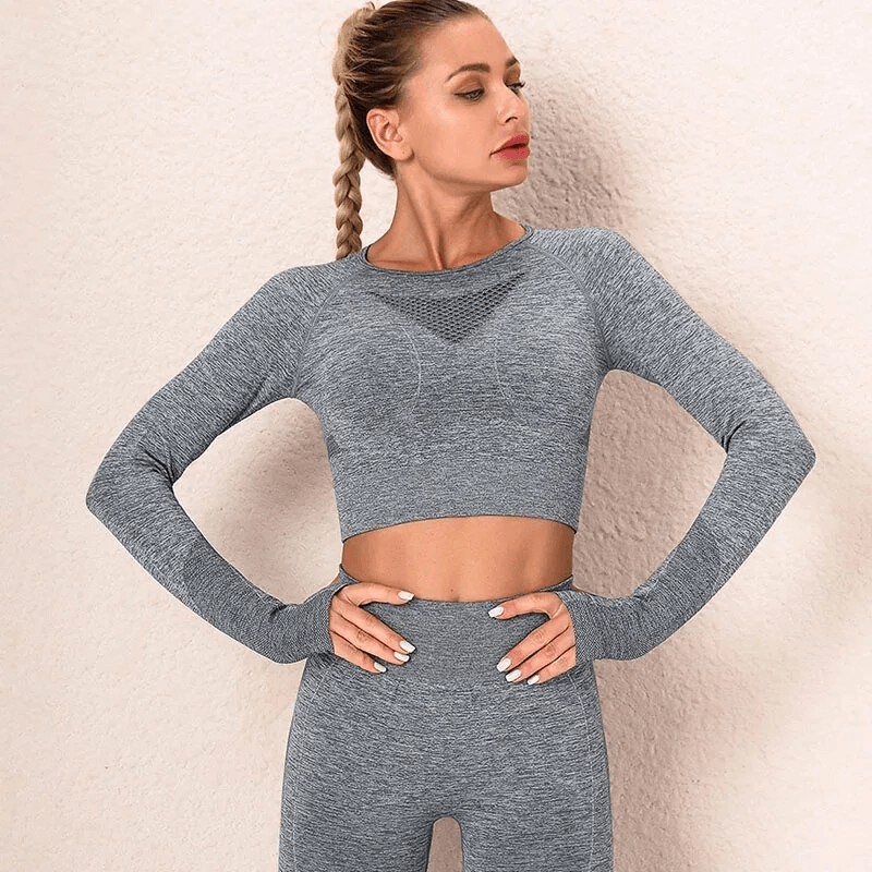 Woman wearing seamless gray yoga set, full-sleeve top and pants, showcasing anti-pilling and windproof material.