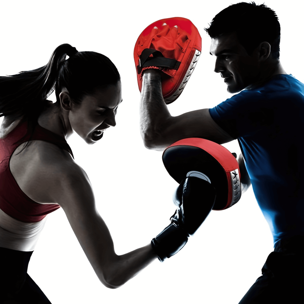 Man and woman sparring with red boxing focus pads during martial arts training