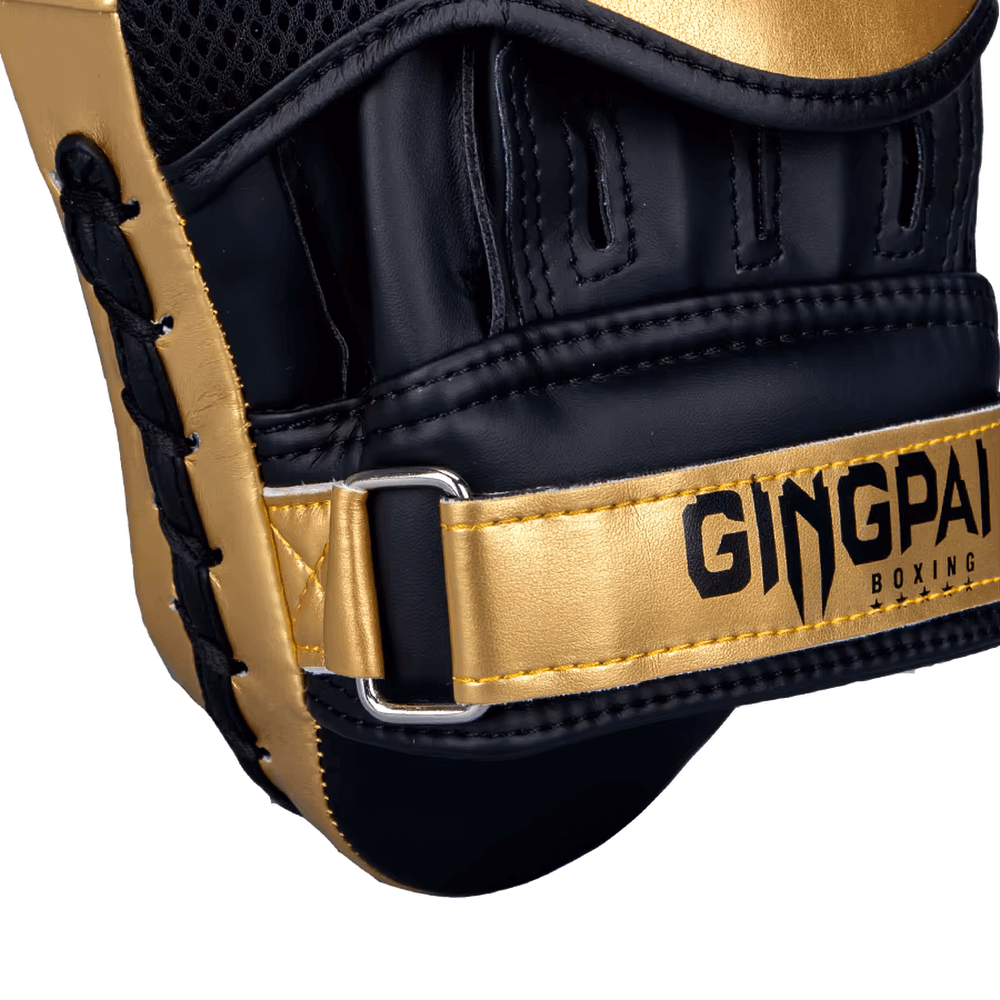Close-up of black and gold boxing mitt with sturdy strap for training and sparring, labeled 'Gingpai Boxing.'