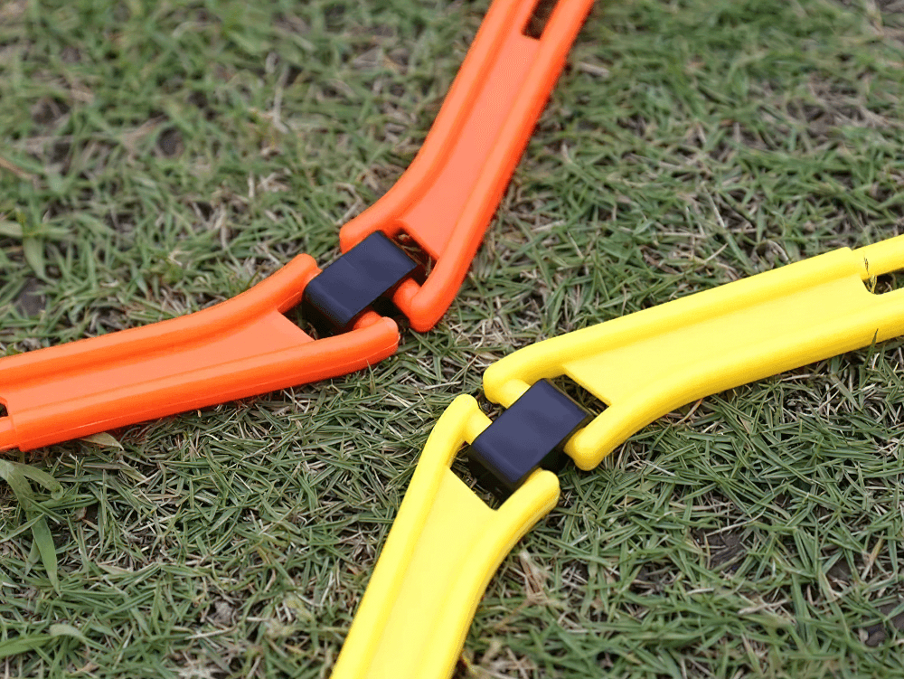 Modular orange and yellow hexagonal hurdles connected on grass for agility training.