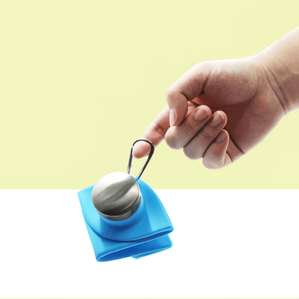 Alt Tag: Hand holding a compact 700ml Foldable Silicone Water Bottle for Outdoor - SF3503 with carabiner clip, perfect for hiking.