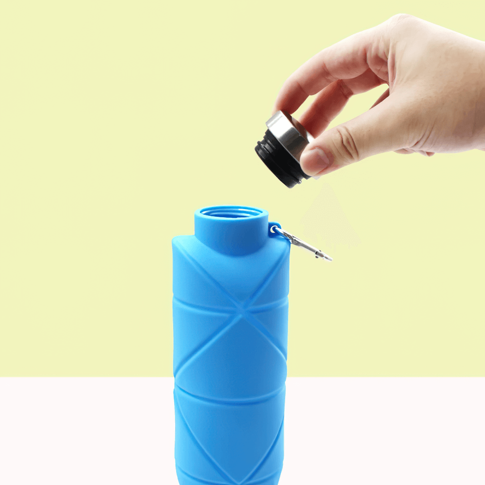 Hand holding cap of 700ml Foldable Silicone Water Bottle for Outdoor - SF3503 with carabiner on a light background