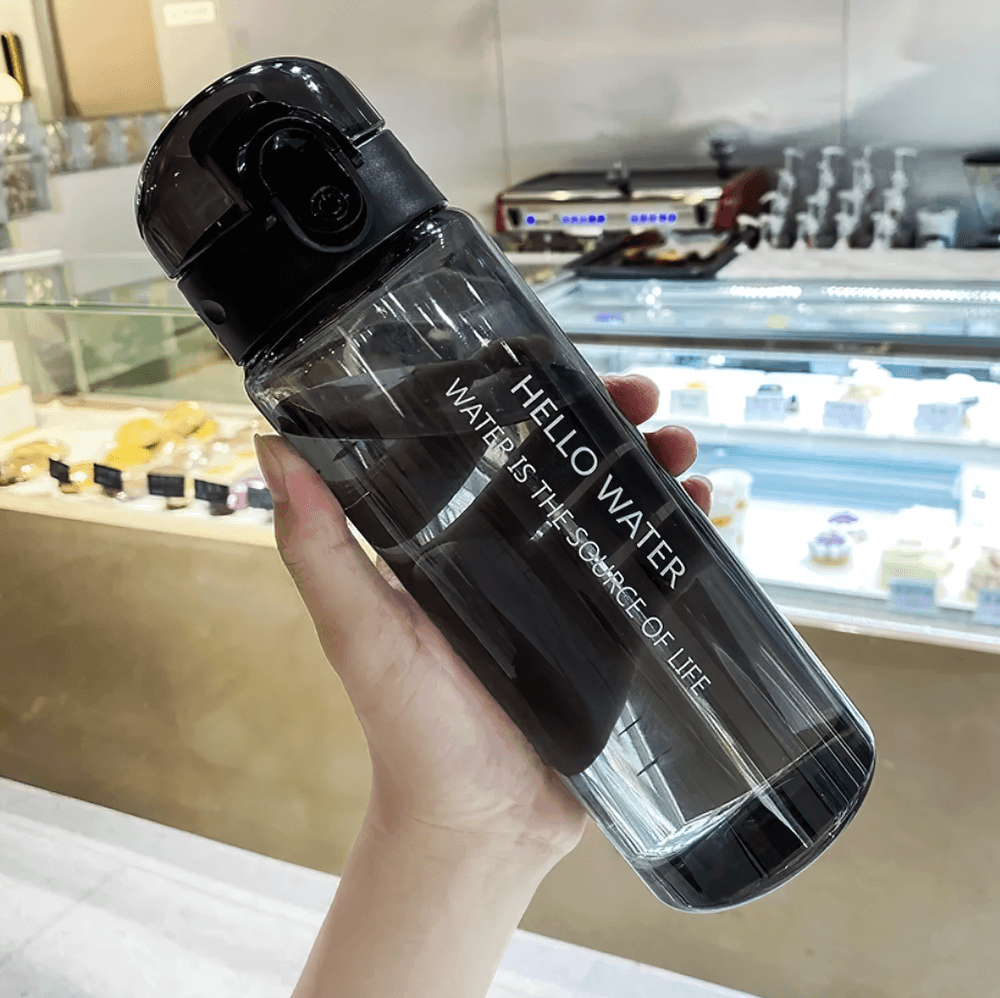 Person holding 780ml sporty reusable water bottle with time marker, ideal for daily hydration and eco-friendly lifestyle.