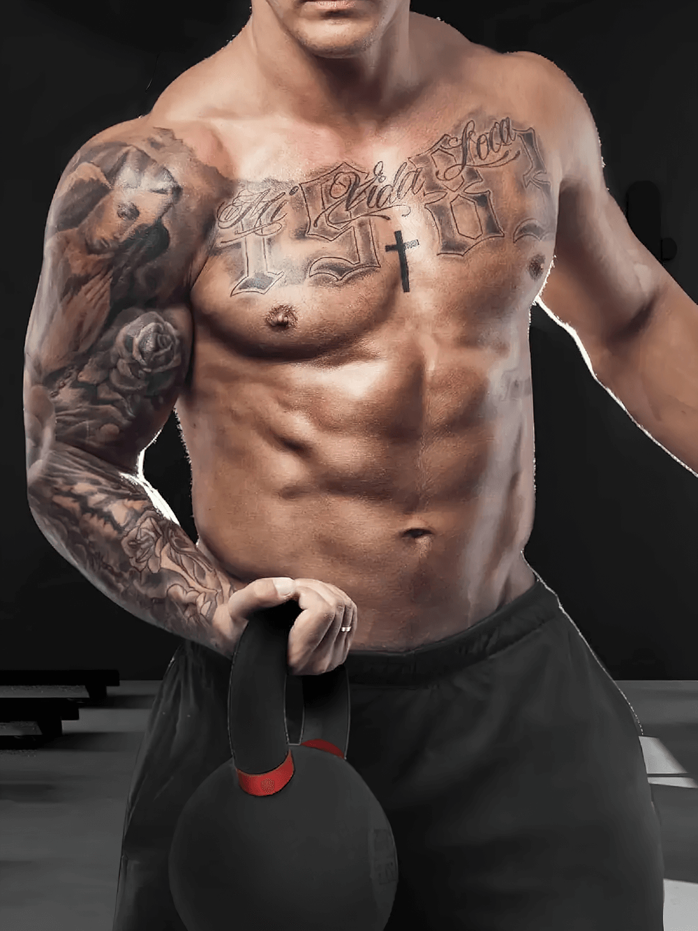 Muscular man holding 79 LB cast iron kettlebell in gym for strength training and workouts.