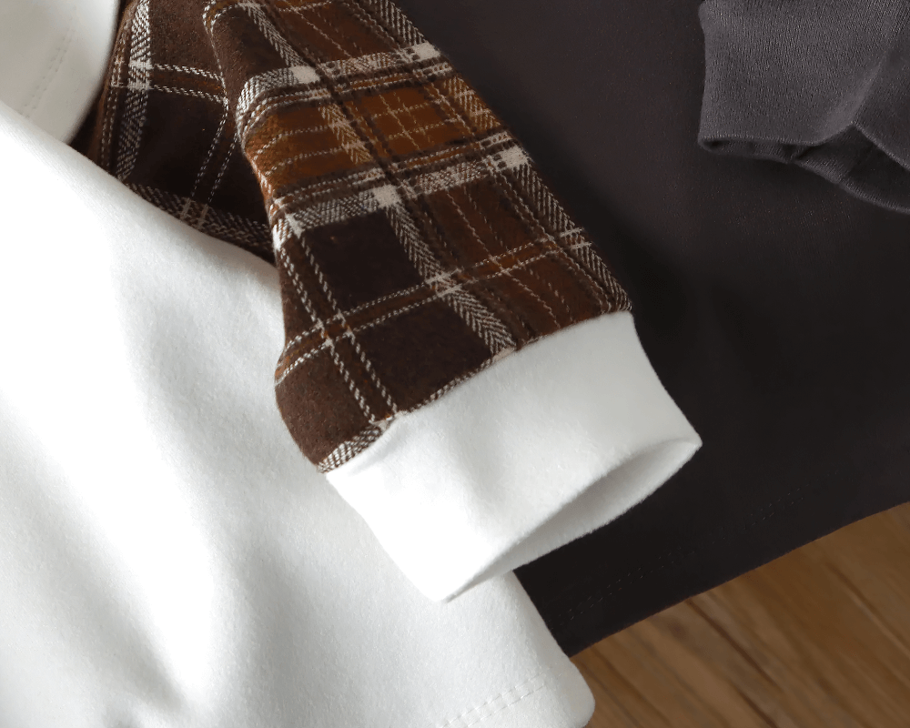 Close-up of children's sweatshirt with white fabric and stylish plaid sleeves, showcasing trendy design for active kids' fashion.