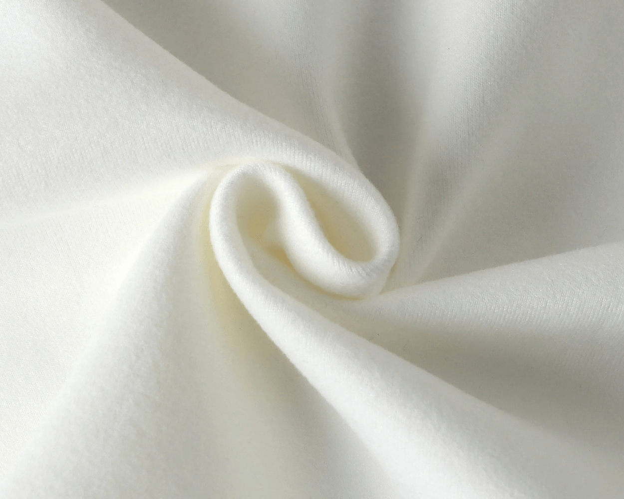 Close-up of soft white fabric texture in a swirl pattern, highlighting the material's smooth and cozy quality.
