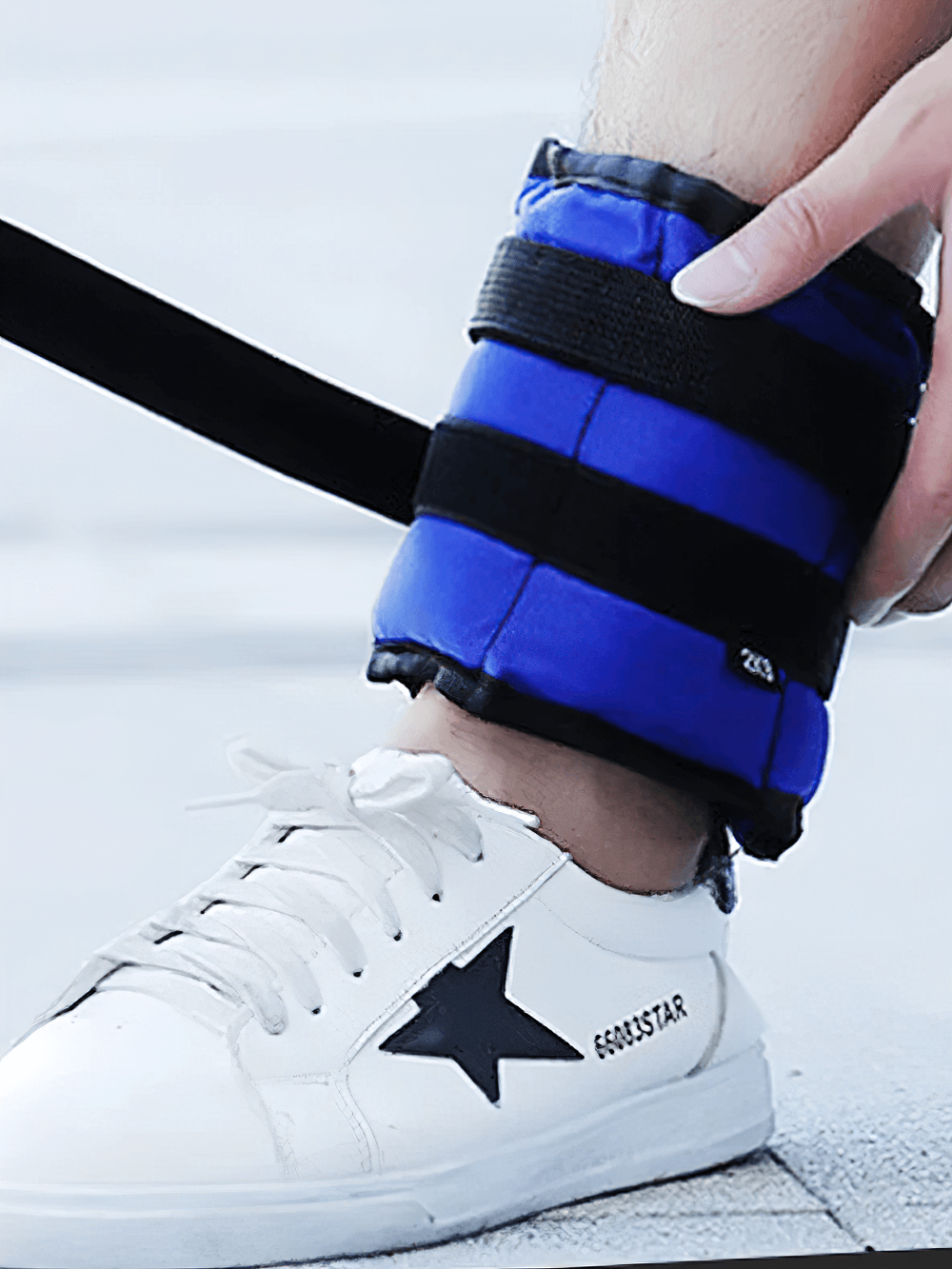 Blue adjustable ankle weight with velcro straps on a shoe, ideal for resistance training and fitness workouts.
