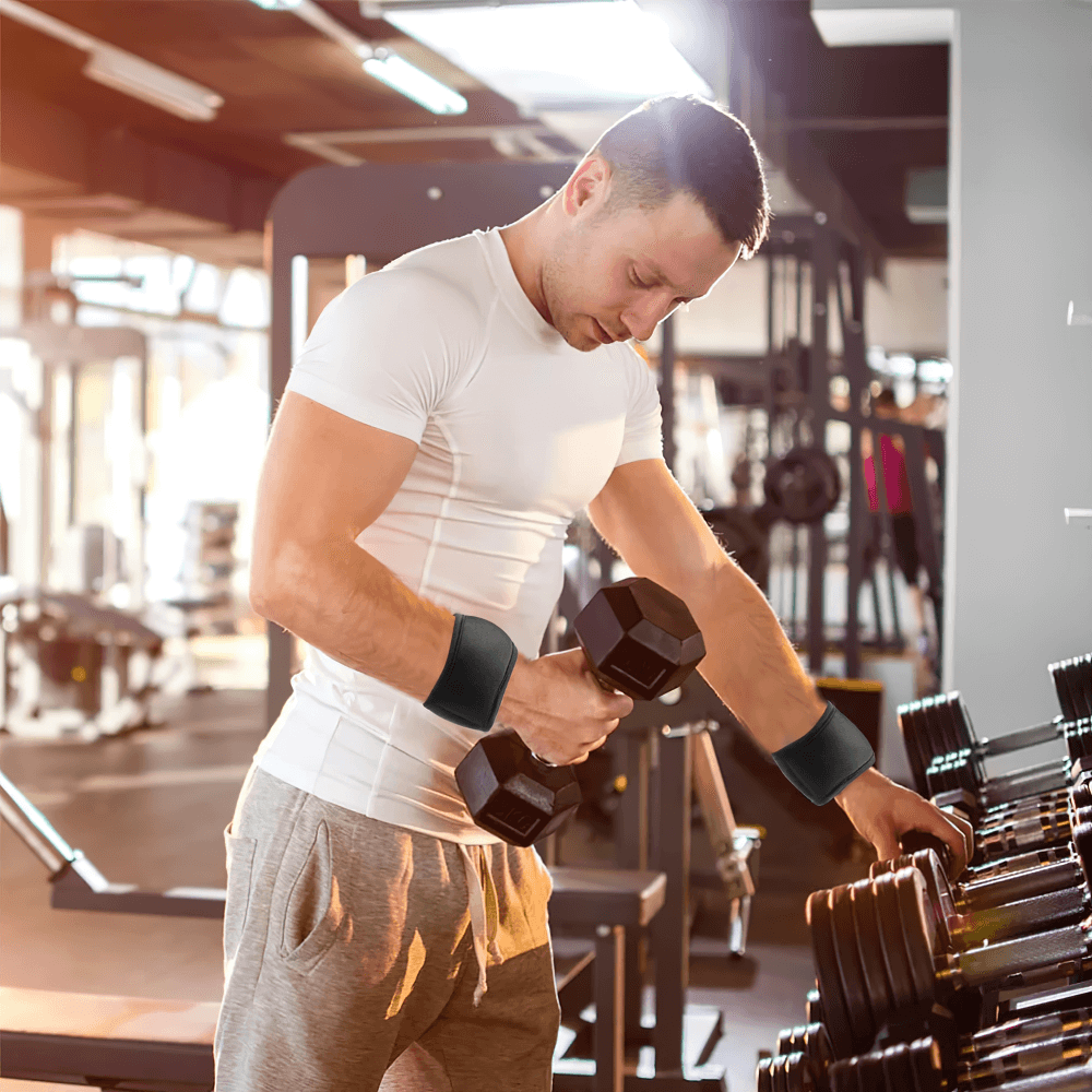 Man using adjustable wrist weights while lifting dumbbells in a gym setting, enhancing workout strength and endurance.