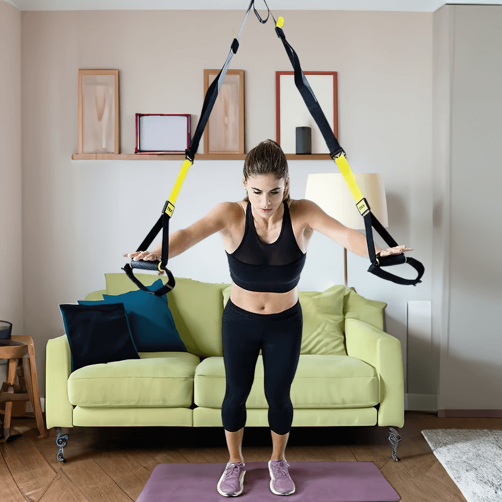 Woman using adjustable suspension training straps for a home workout in living room, showcasing strength and balance exercises.