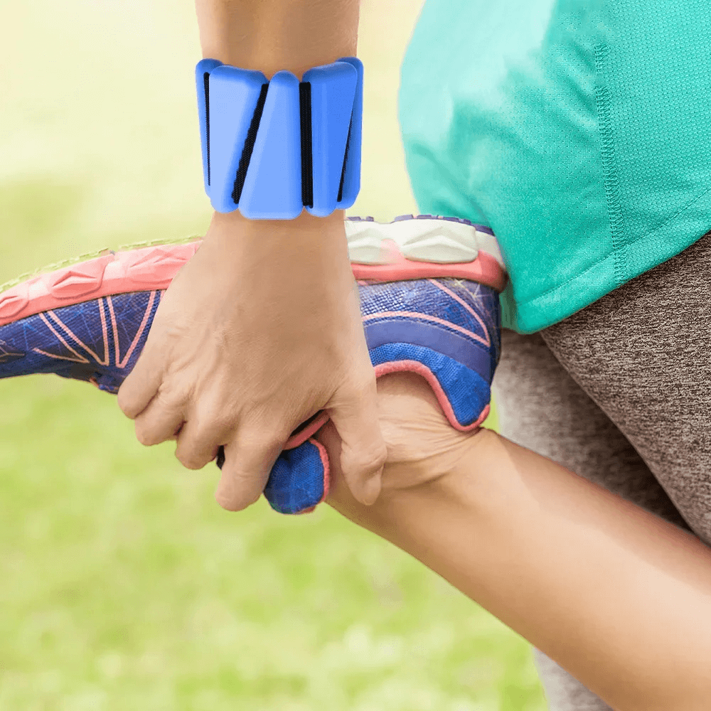 Person stretching leg while wearing blue adjustable wrist weights for cardio and resistance training.
