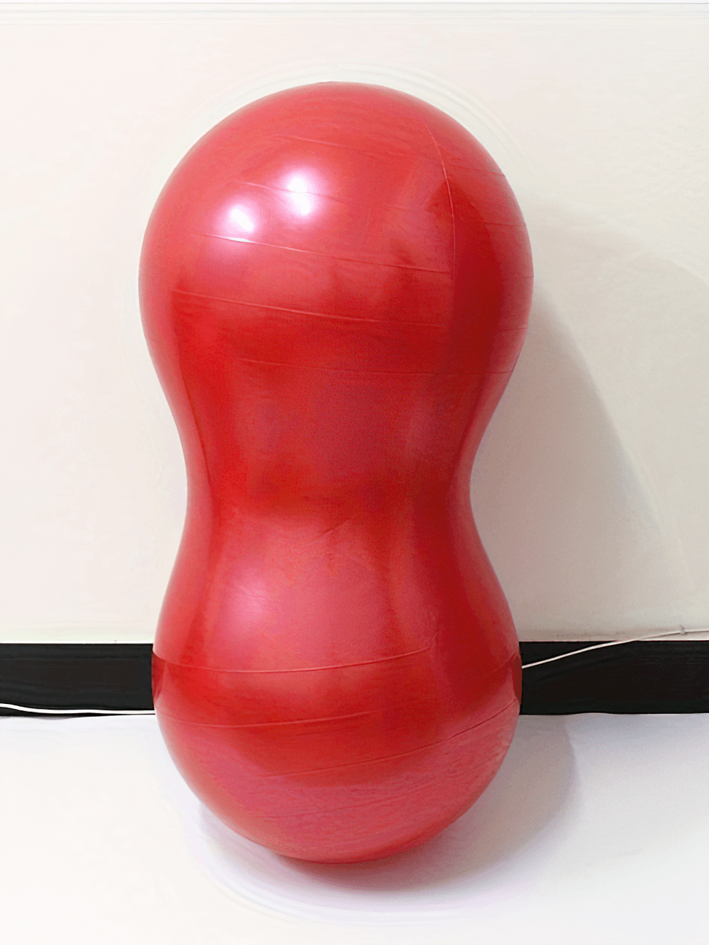 Red anti-explosion peanut-shaped yoga ball for fitness, enhancing core strength, flexibility, and stability during workouts.