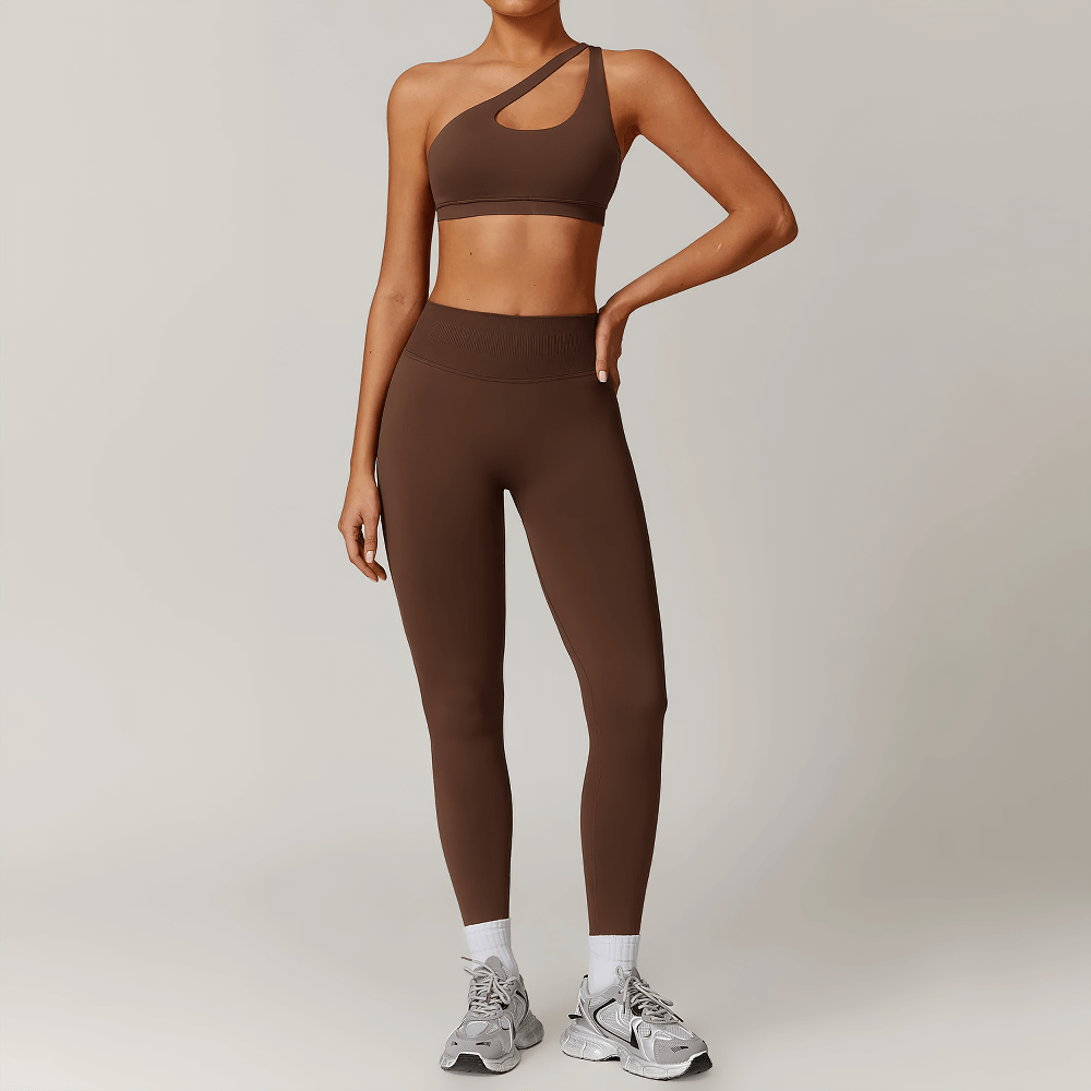 Model wearing brown asymmetric one-shoulder sports bra and leggings set for workouts, showcasing seamless design and contoured fit.