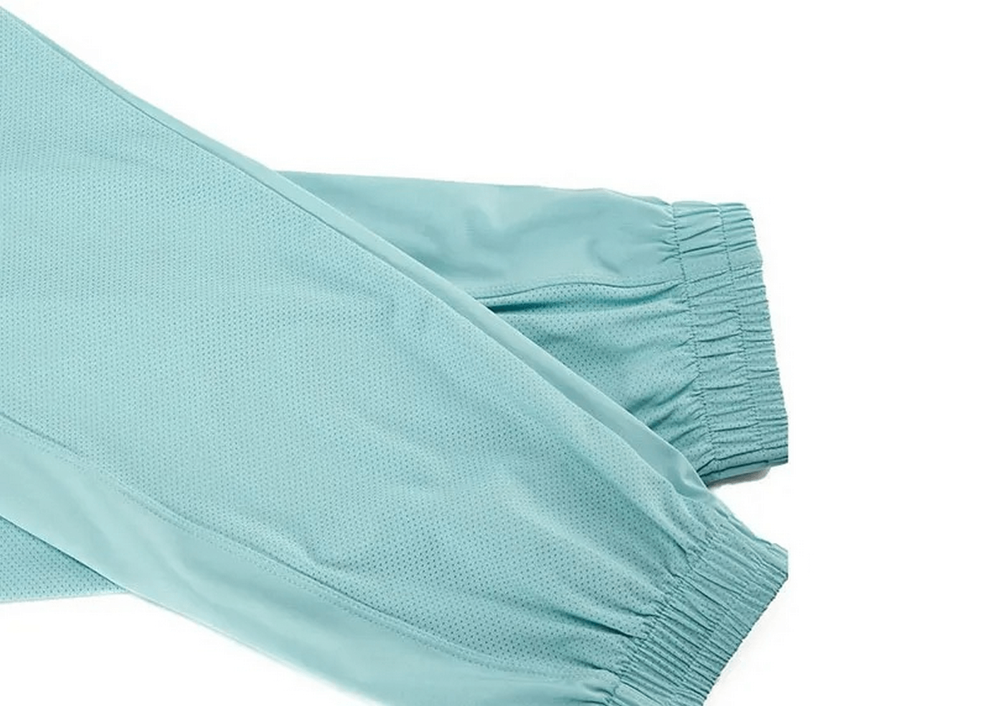 Close-up of light blue breathable athletic pants from a stylish three-toned sports clothing set for women, featuring elastic cuffs.