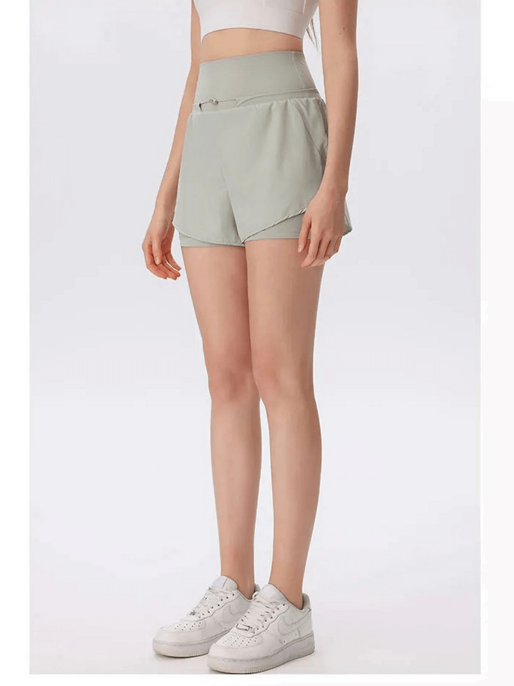 Woman wearing high waist athletic shorts in light green for gym or outdoor activities.