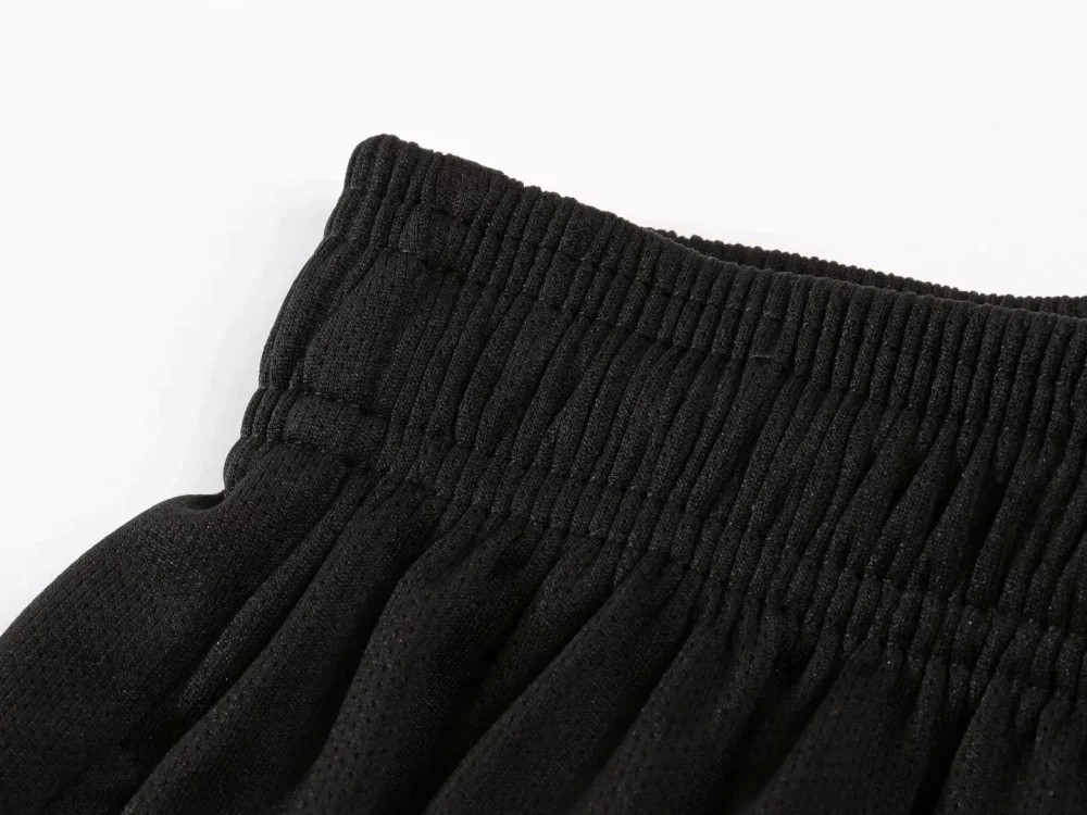 Close-up of elastic waistband on black athletic shorts, showcasing breathable polyester fabric for sports and gym wear.
