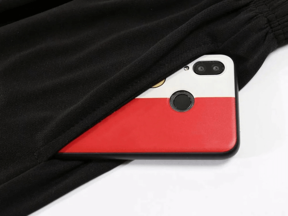 Black athletic pants with a smartphone partly inside the pocket, showcasing the functional design ideal for sports and outdoor activities.