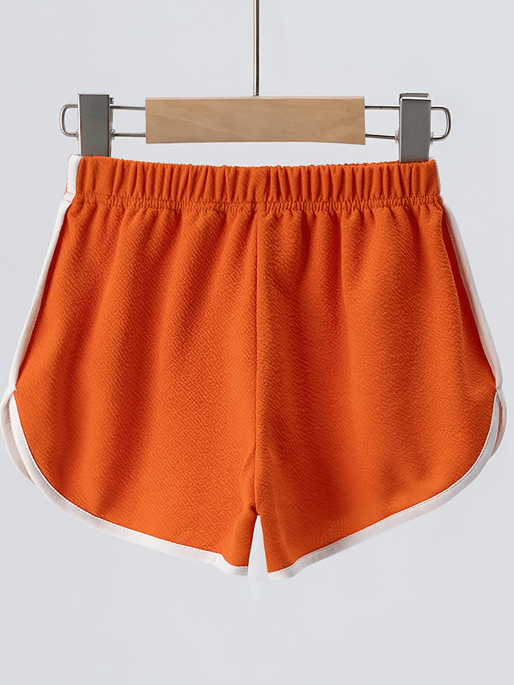 Athletic Shorts With Elastic Waist and Side Trim - SF3732 in orange with white trim hanging on a wooden hanger.