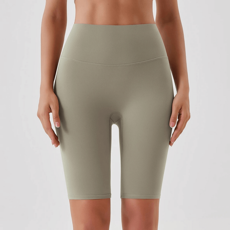 Woman wearing olive athletic high-waisted tight shorts, perfect for yoga and running, showcasing a comfortable nylon blend fabric.