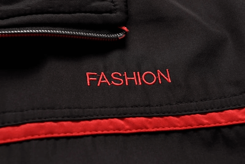 Close-up of stylish black and red tracksuit fabric with 'FASHION' text embroidery, showcasing quality and trendy design details.