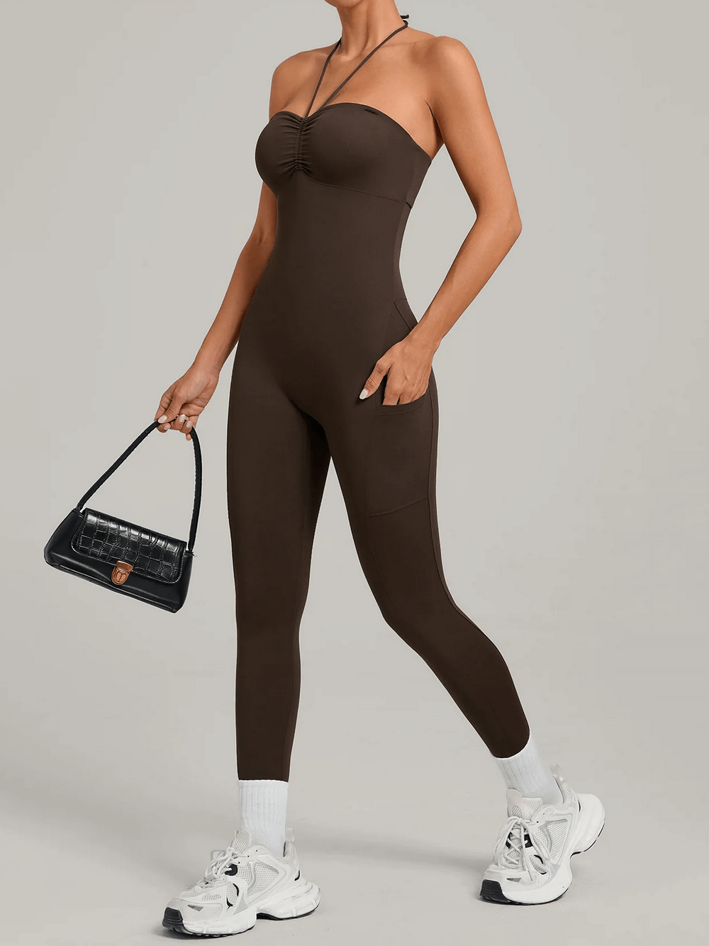 Model wearing Backless Yoga Jumpsuit with Pockets and Halter - SF4261, holding a handbag, showcasing sleek and comfy activewear style.