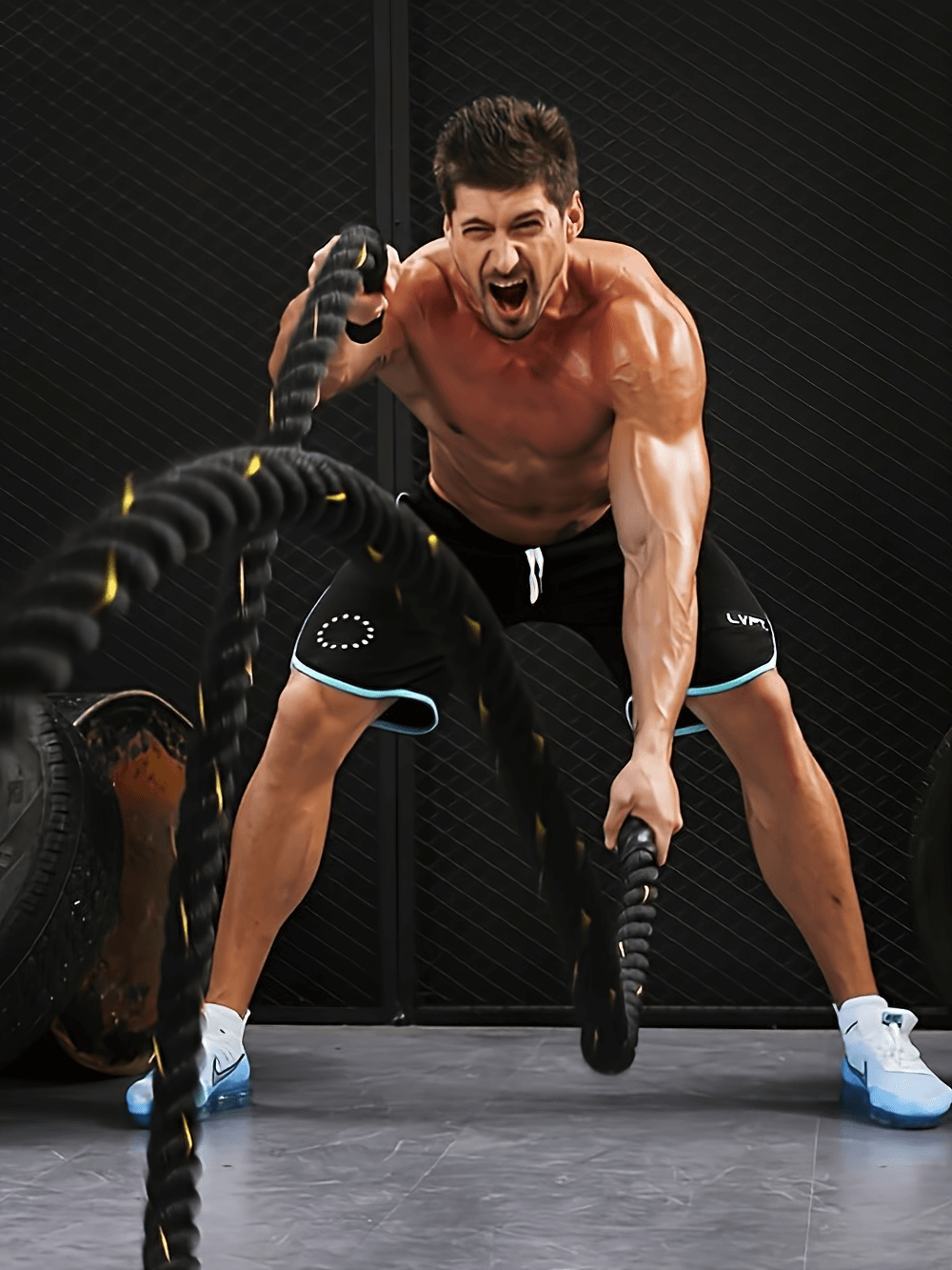 Man using heavy-duty battle rope for strength training and core workout, showcasing intense exercise and endurance.