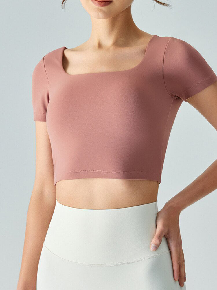 Woman wearing a rose pink hollow-back yoga T-shirt, short sleeves, and sports crop top made of breathable, quick-drying nylon and spandex.
