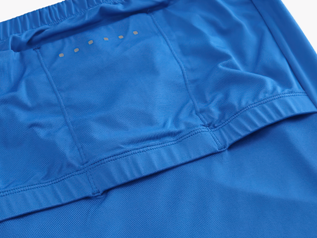 Close-up of blue cycling apparel fabric with breathable mesh, depicting quick-drying properties for men's summer rides.