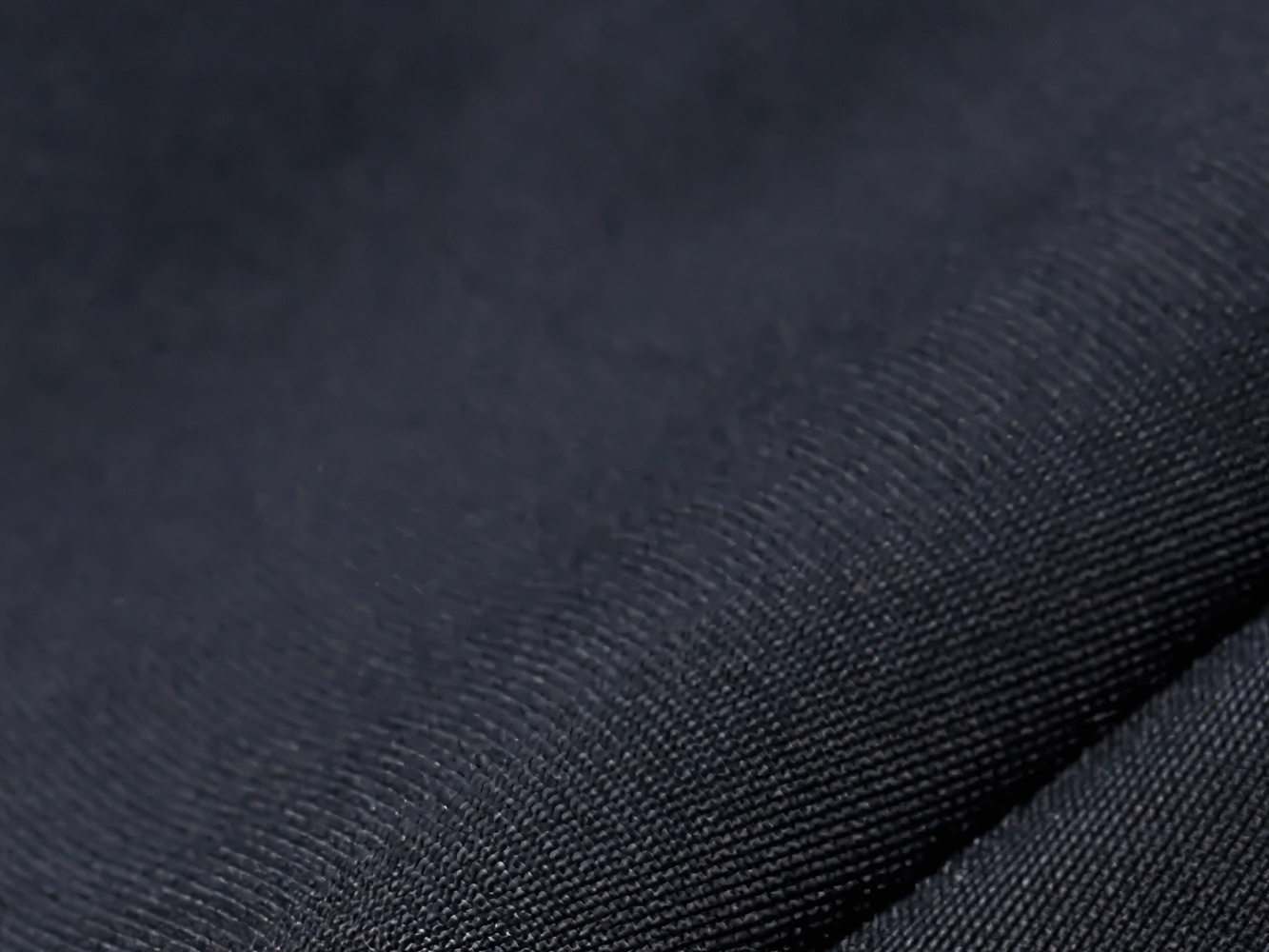 Close-up of black polyester fabric texture for men's cycling apparel, highlighting breathable and quick-drying material.