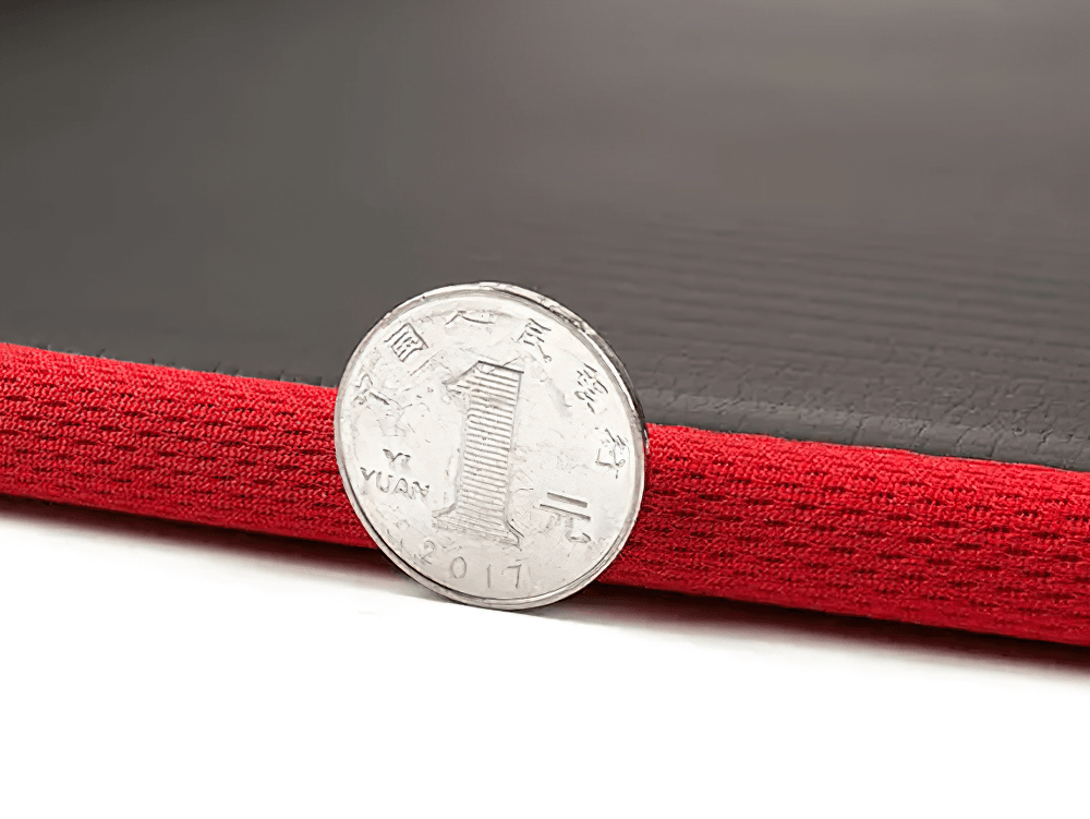 Close-up of black and red non-slip yoga mat with coin for thickness comparison, highlighting durable build and cushioning.