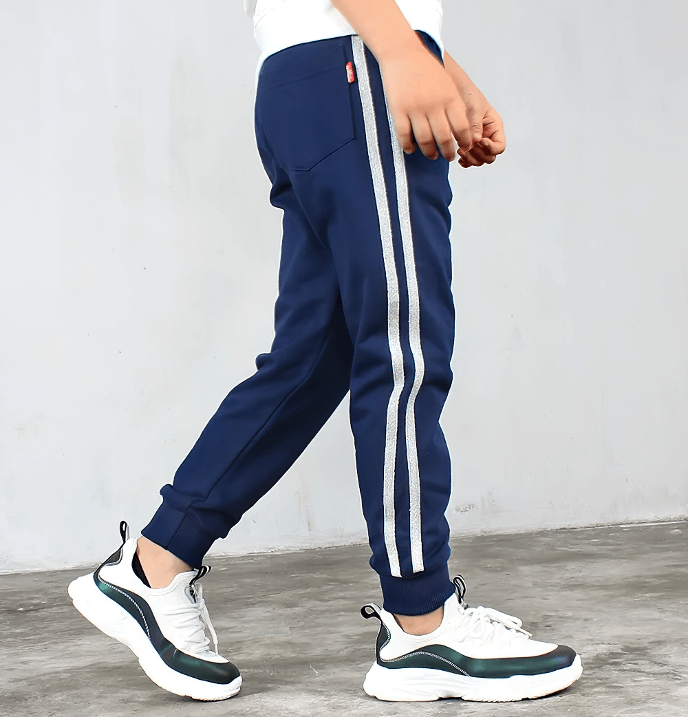 Side view of navy Boys Athletic Jogger Sweatpants with Pockets - SF3611, featuring white stripes and worn by a child with sneakers.