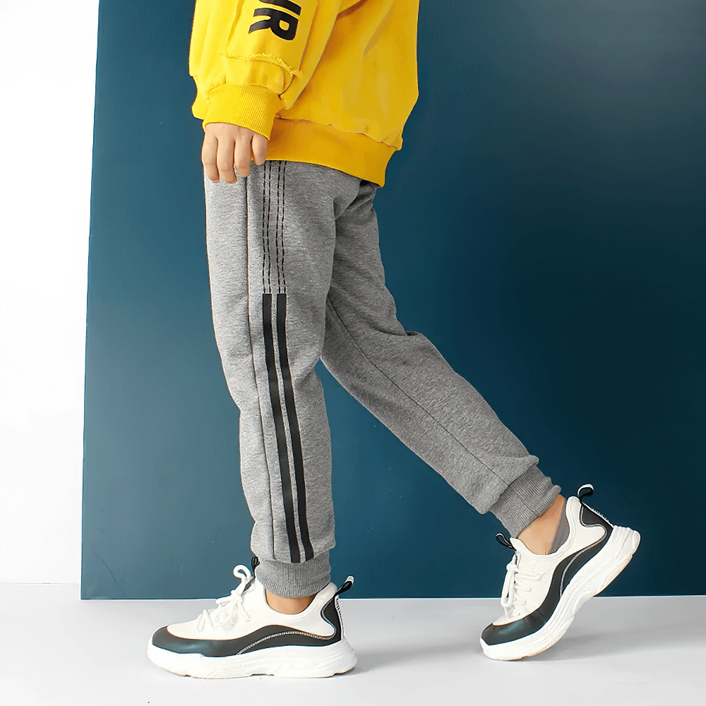 Boy wearing Boys Athletic Jogger Sweatpants with Pockets - SF3611, gray with black stripes, showing side profile with pockets and elastic waistband.