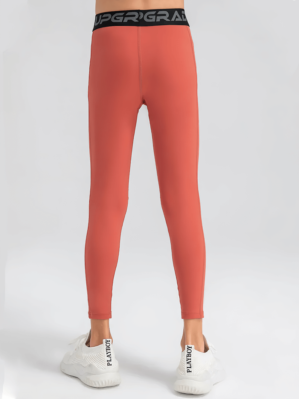 Back view of Boys Compression Sports Leggings for Training - SF3794 in coral color, showing elastic waist and full-length fit.