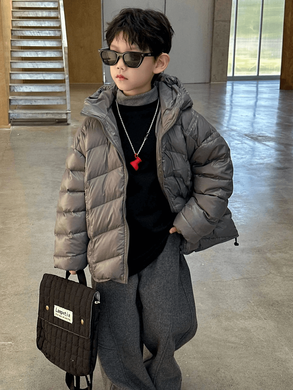 Young boy wearing a stylish Boys Hooded Down Puffer Jacket With Zipper - SF3638, perfect for winter adventures, holding a trendy bag.