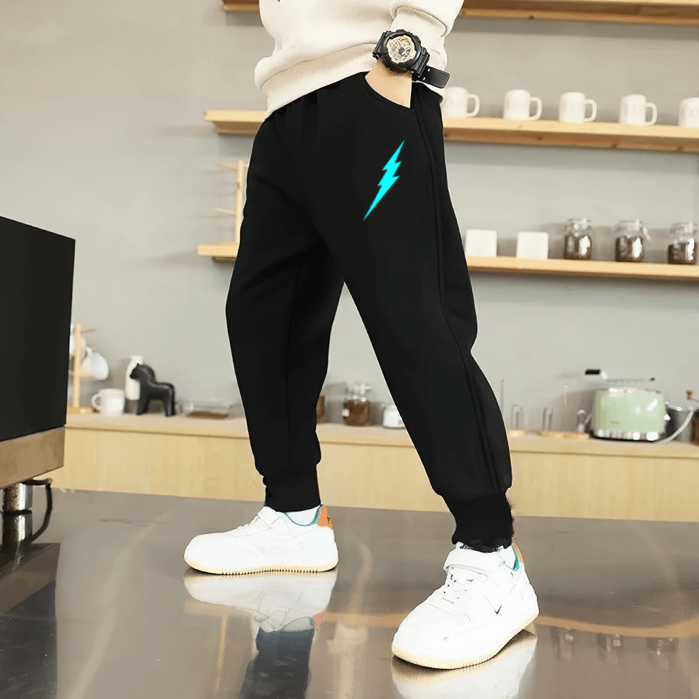 Boy wearing Boys Sporty Jogger Pants with Luminous Prints - SF3724, featuring lightning print and elastic waist, standing in a modern kitchen.