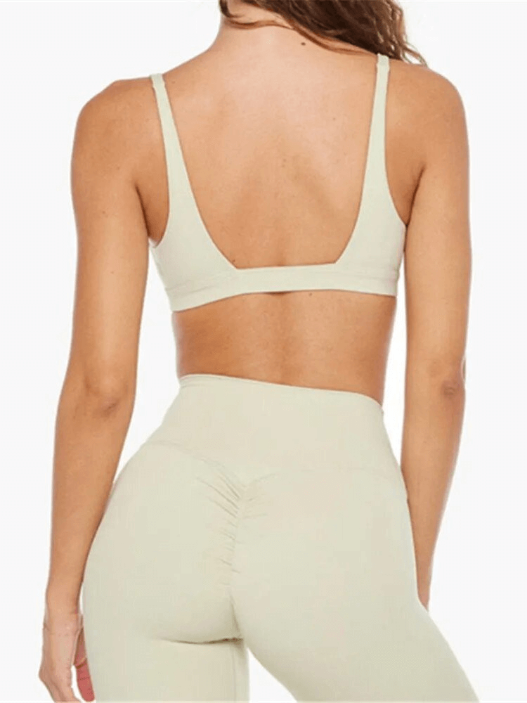 Back view of model wearing breathable elastic women's sports bra and shorts in beige, showcasing support and comfort for yoga.