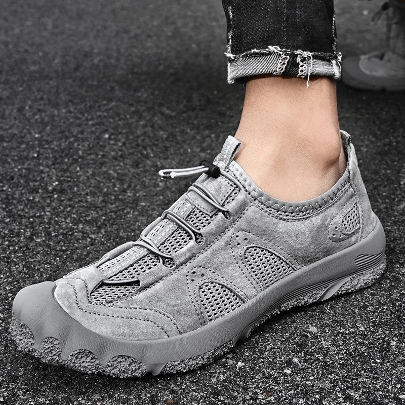 Stylish grey breathable leather hiking sneaker with adjustable lace and sturdy sole on pavement.