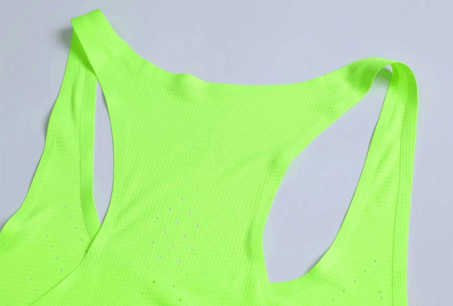 Vibrant neon tank top close-up showcasing athletic fit and breathable perforated design for optimal airflow during workouts.