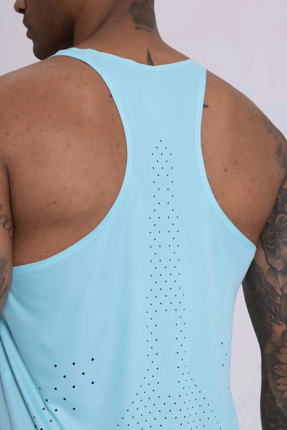 Back view of a man wearing a breathable blue athletic tank top with perforated design, showcasing flexibility and style.