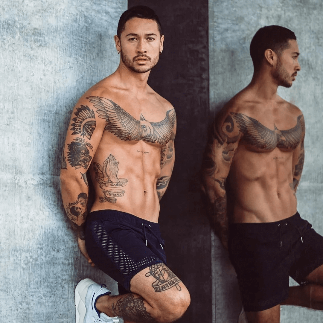 Man wearing Breathable Mesh Black Athletic Shorts SF2157, showcasing tattoos and style against a concrete background