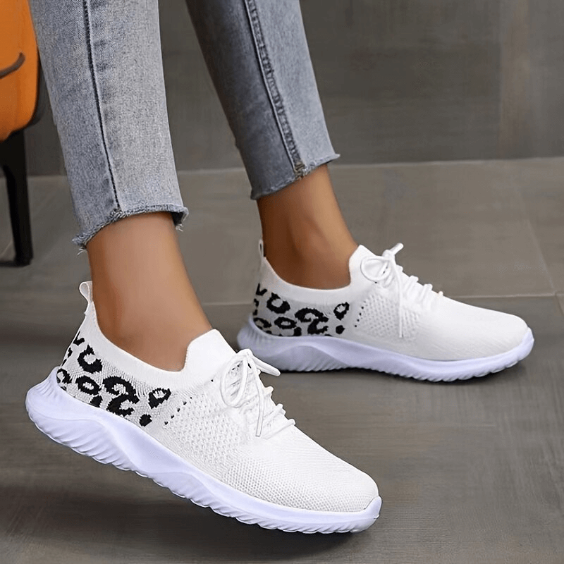 Woman wearing breathable mesh leopard print soft sole sneakers with lace-up closure, showcasing comfort and style.