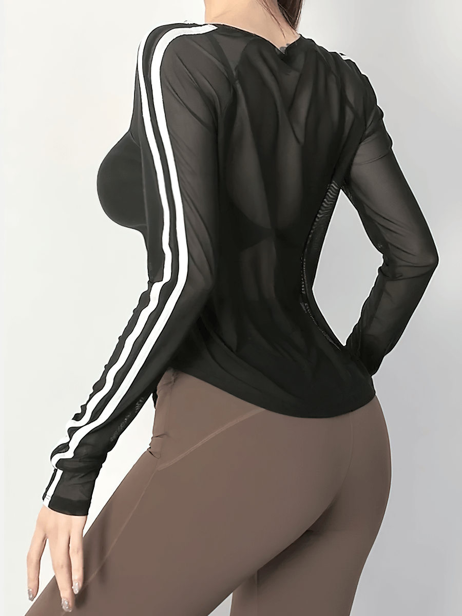 Woman wearing black breathable mesh yoga top with full sleeves and stripe detail, paired with brown leggings.