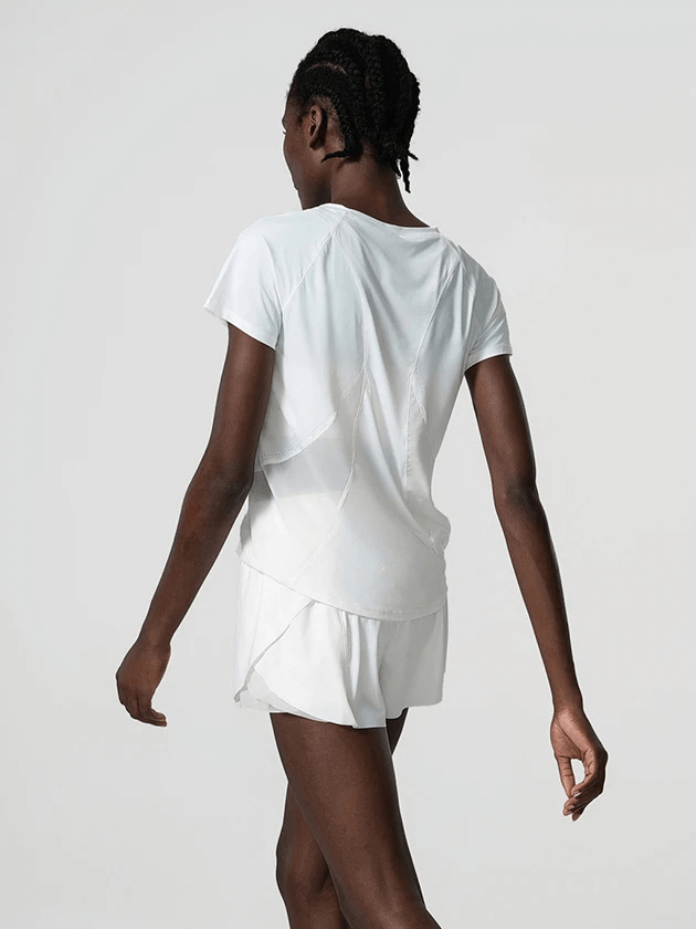 Back view of woman in white breathable nylon gym wear for yoga and running, featuring short sleeves and solid pattern, walking confidently.