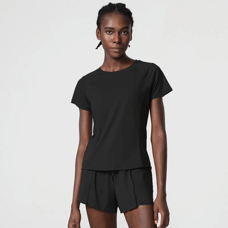 Woman in black breathable nylon gym wear for yoga and running, featuring short sleeves and loose fit. Anti-wrinkle and quick-dry features.